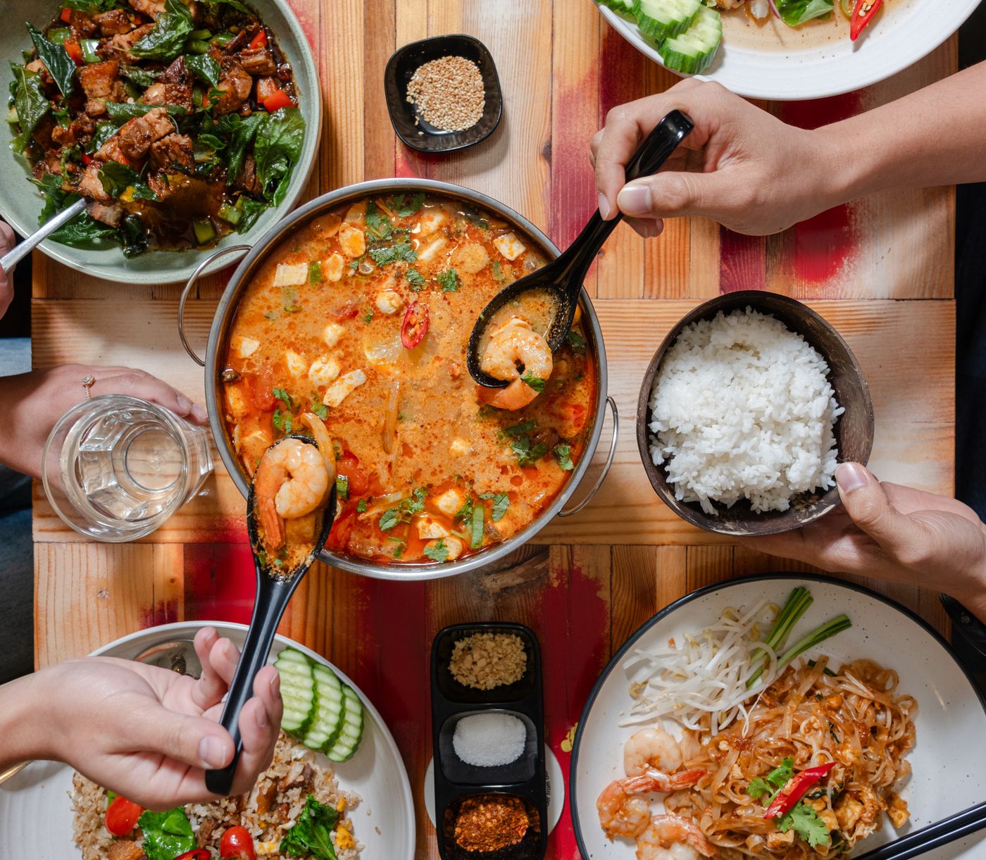 Tom Yum pot, Pad Thai and jasmine rice shared on the table at Phicha